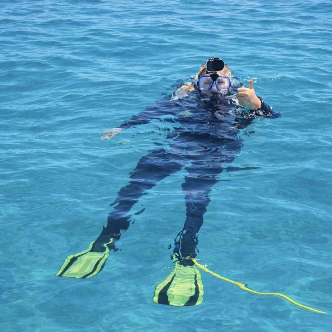 Tayden Franklin floating in clear blue water in his scuba gear, giving a thumbs up